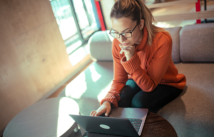 Person sitting on a couch looking at a laptop